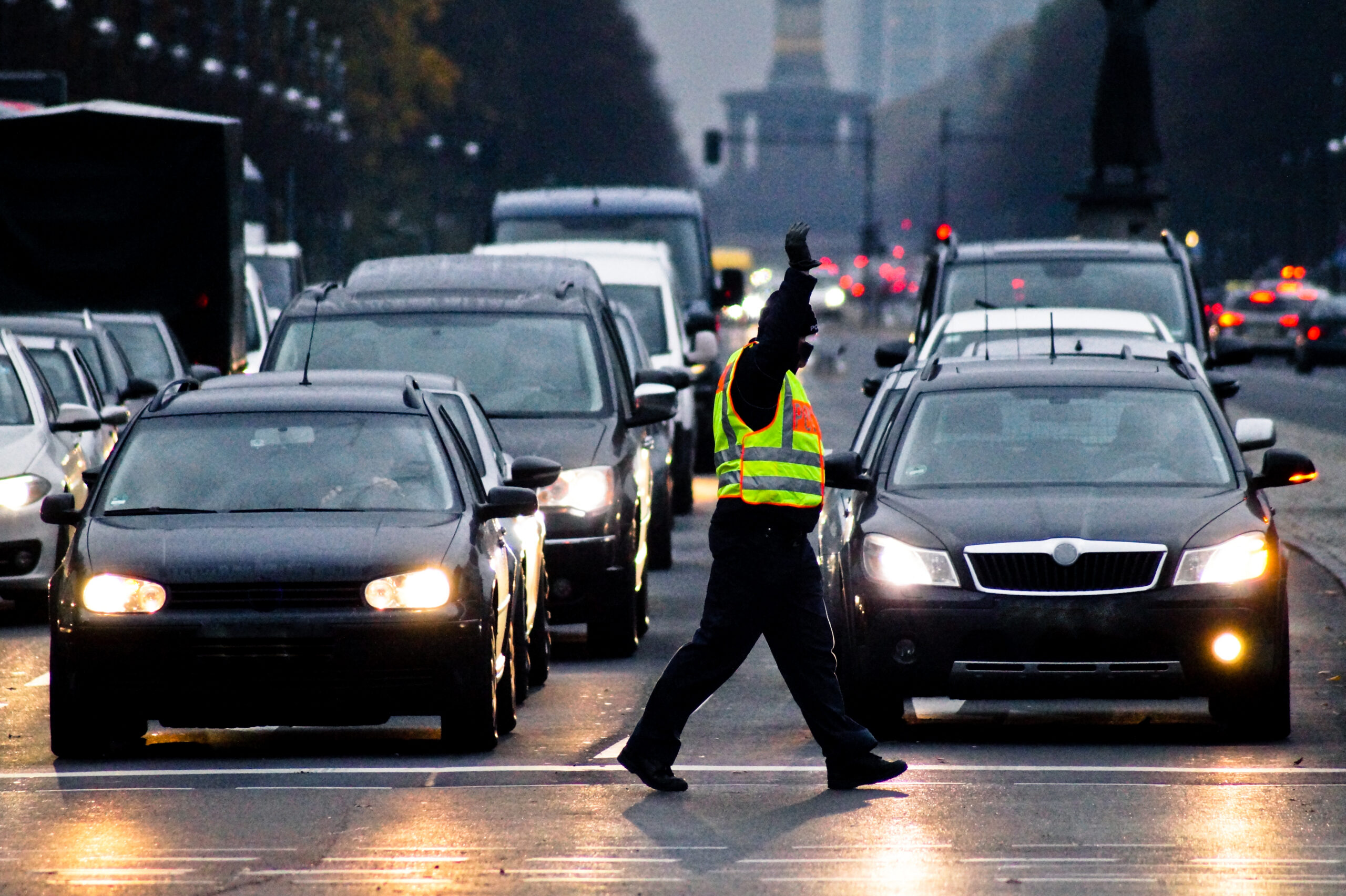 traffic-cop-walking-by-illuminated-cars-city-street-dusk – SSPTMS pedestrian traffic management NYC